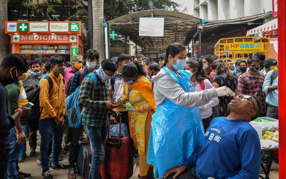 A health official conducts a Covid-19 coronavirus screening of a passenger at a railway station, as omicron is detected in the state of Karnataka - MANJUNATH KIRAN/AFP via Getty Images