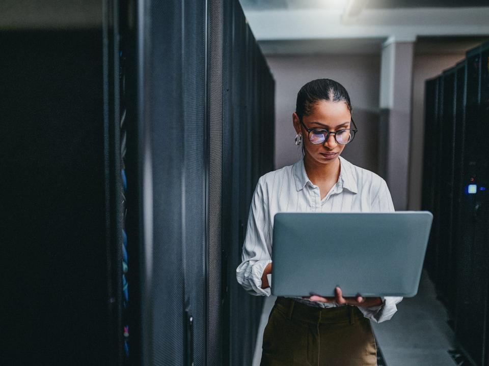 Tech worker holding a laptop in a server room