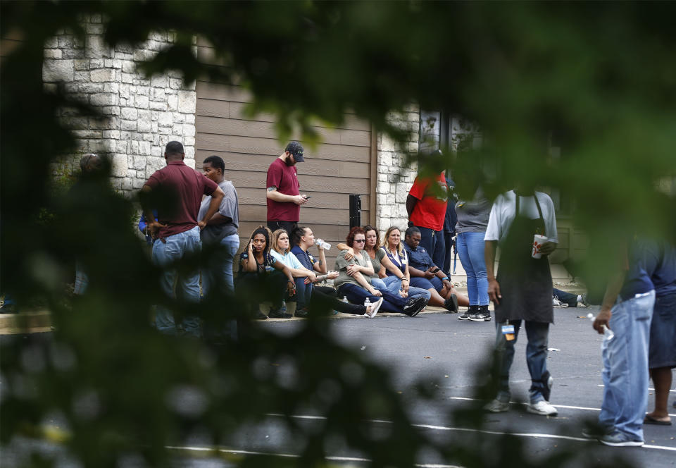 Walmart employees and family members sit in a nearby parking lot following a shooting at the store, Tuesday, July 30, 2019, in Southaven, Miss. A gunman fatally shot two people and wounded a police officer before he was shot and arrested Tuesday at the Walmart in northern Mississippi, authorities said. (Mark Weber/Daily Memphian via AP)