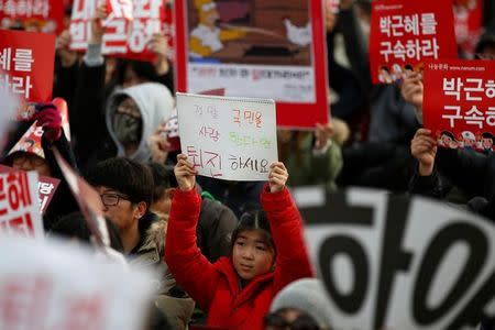 A girl holds up a hand-written message during a protest calling for South Korean President Park Geun-hye to step down in central Seoul, South Korea, December 3, 2016. The message reads: "If you really love people, step down". REUTERS/Kim Hong-Ji