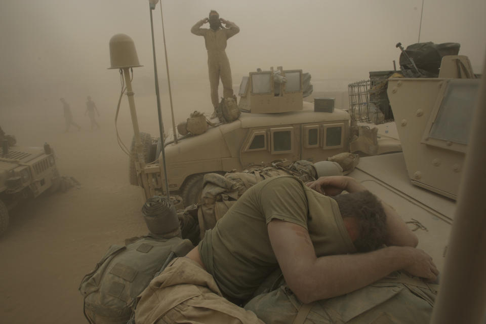 U.S. Marines from the 24th Marine Expeditionary Unit try to take shelter from a sand storm at forward operating base Dwyer in the Helmand province of southern Afghanistan on May 7, 2008. (AP Photo/David Guttenfelder, File)