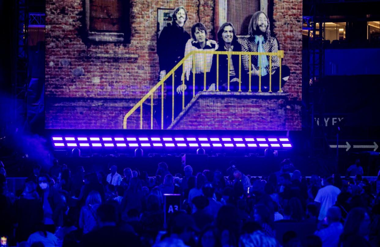 A slide show featuring Paul McCartney and his former band, The Beatles , entertains the crowd before the concert.