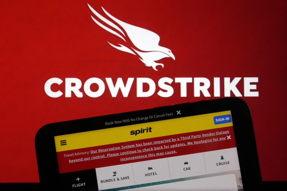 The logo for CrowdStrike and a Spirit Airlines webpage with a Travel Advisory about a third Party Outage impacting their Reservation System are shown on a computer screen and mobile phone screen, in New York, Friday, July 19, 2024. (AP Photo/Richard Drew)