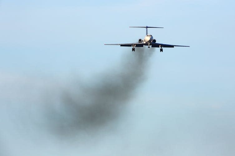 An aeroplane with black exhaust fumes.