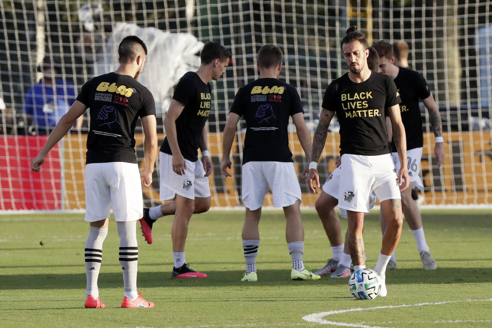 Montreal Impact players warm up wearing Black Lives Matter t-shirts before an MLS soccer match against Orlando City, Saturday, July 25, 2020, in Kissimmee, Fla. (AP Photo/John Raoux)