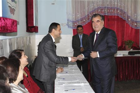 Tajikistan's President Imomali Rakhmon (R) receives his ballot from an electoral official during the presidential election in Dushanbe, in this November 6, 2013 handout photograph provided by Press Service of presidential administration of Tajikistan. REUTERS/Press Service of presidential administration of Tajikistan/Handout via Reuters