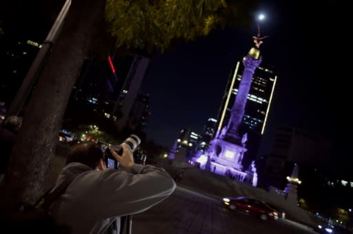 A man taking pictures of the Super Moon during the start of the total lunar eclipse, at the Angel de la Independencia in Mexico City