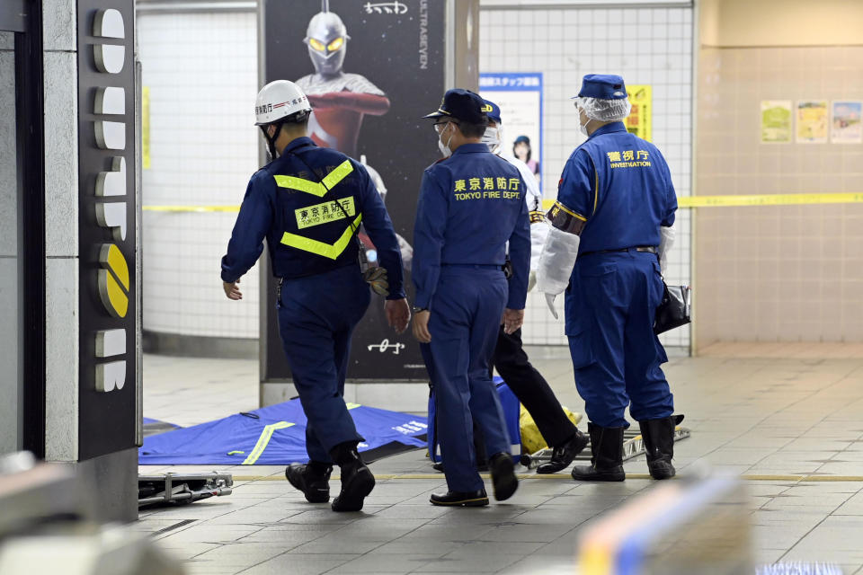 Tokyo Fire Department personnel and a police investigator, right, move toward a platform at Soshigaya Okura Station after stabbing on a commuter train, in Tokyo Friday, Aug. 6, 2021. A man with a knife stabbed passengers on a commuter train Friday and was arrested by police after fleeing, fire department officials and news reports said. (Kyodo News via AP)