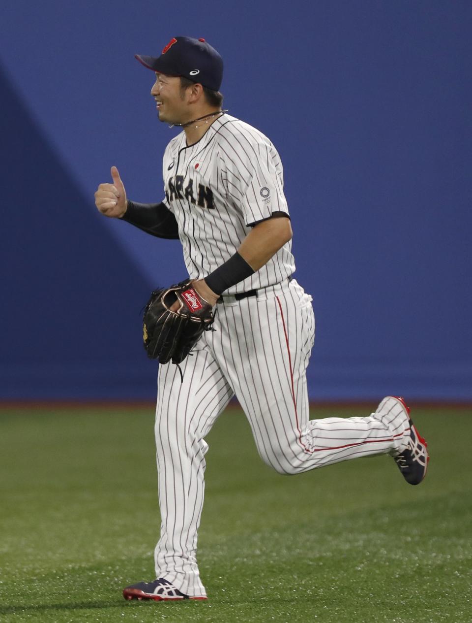Japan outfielder Seiya Suzuki gives a thumbs up while running on the field