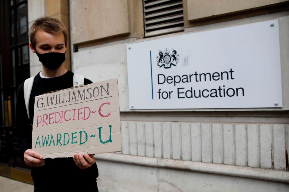 A student holds a sign about downgraded results (AFP via Getty Images)