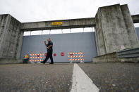 A Plaquemines Parish sheriff deputy walks away after workers closed a floodwall gate on Hwy 39 in Poydras, La., Wednesday, Oct. 28, 2020. Hurricane Zeta is expected to make landfall this afternoon as a category 2 storm. (AP Photo/Gerald Herbert)