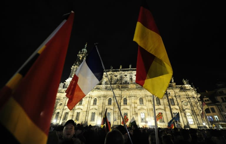 Supporters of the Islamophobic PEGIDA movement hold German and french flags during a demonstration in Dresden, eastern Germany, on November 16, 2015