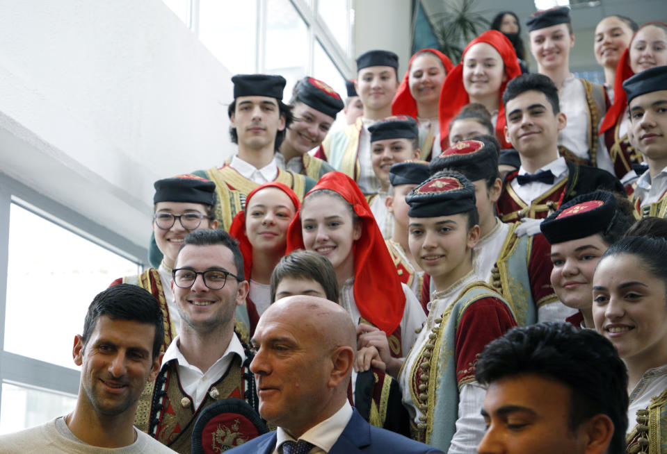 Serbian tennis player Novak Djokovic, bottom left, poses with top local official Marko Carevic, bottom center, and children in the municipal building in Budva, Montenegro, Friday, Jan. 28, 2022. Djokovic arrived to receive a plaque declaring him an honorary citizen of the town. (AP Photo/Risto Bozovic)