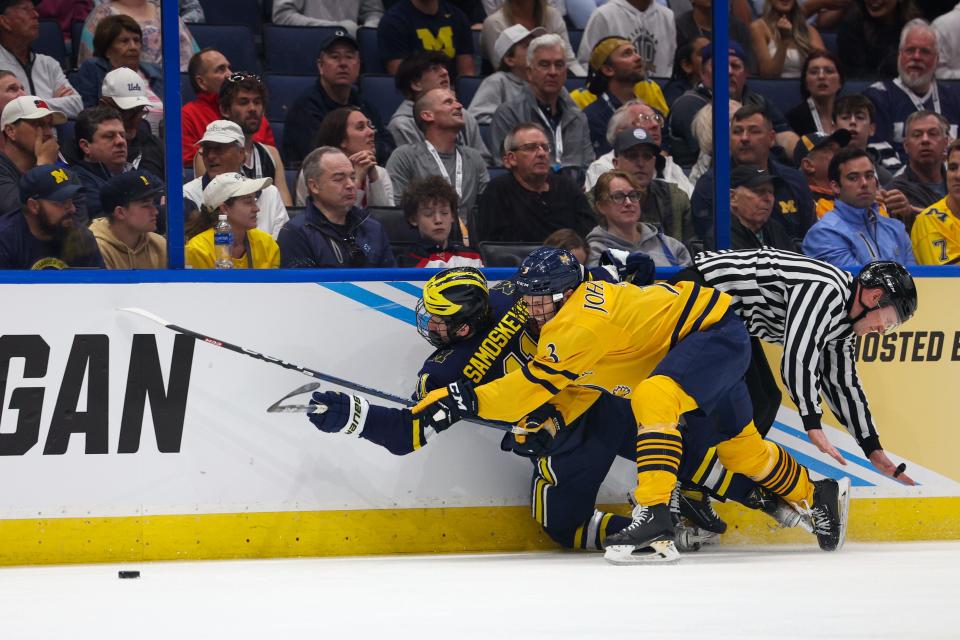 Michigan forward Mackie Samoskevich (11) and Quinnipiac defenseman Jake Johnson (3) collide into the wall during the first period in the semifinals of the 2023 Frozen Four at Amalie Arena in Tampa, Florida, on Thursday, April 6, 2023.