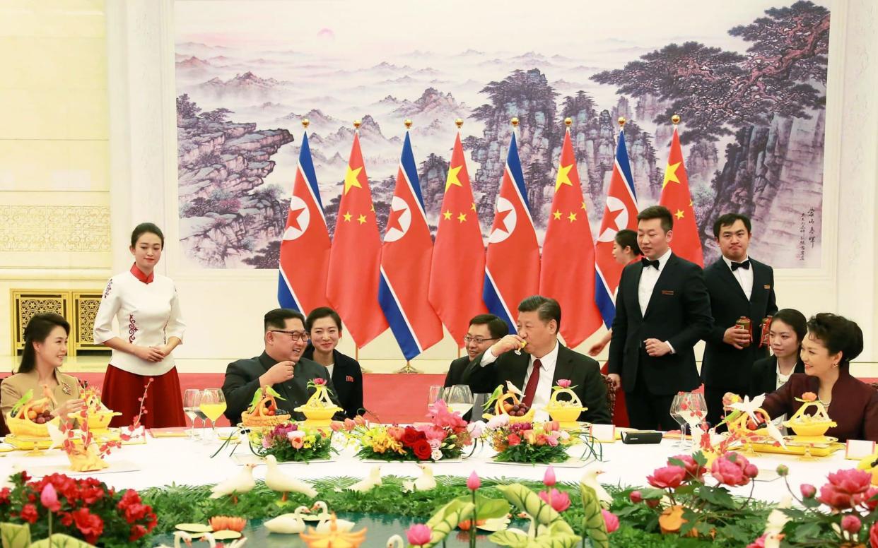 Xi Jinping drinks a glass of baijiu as Kim Jong-un looks on - AFP