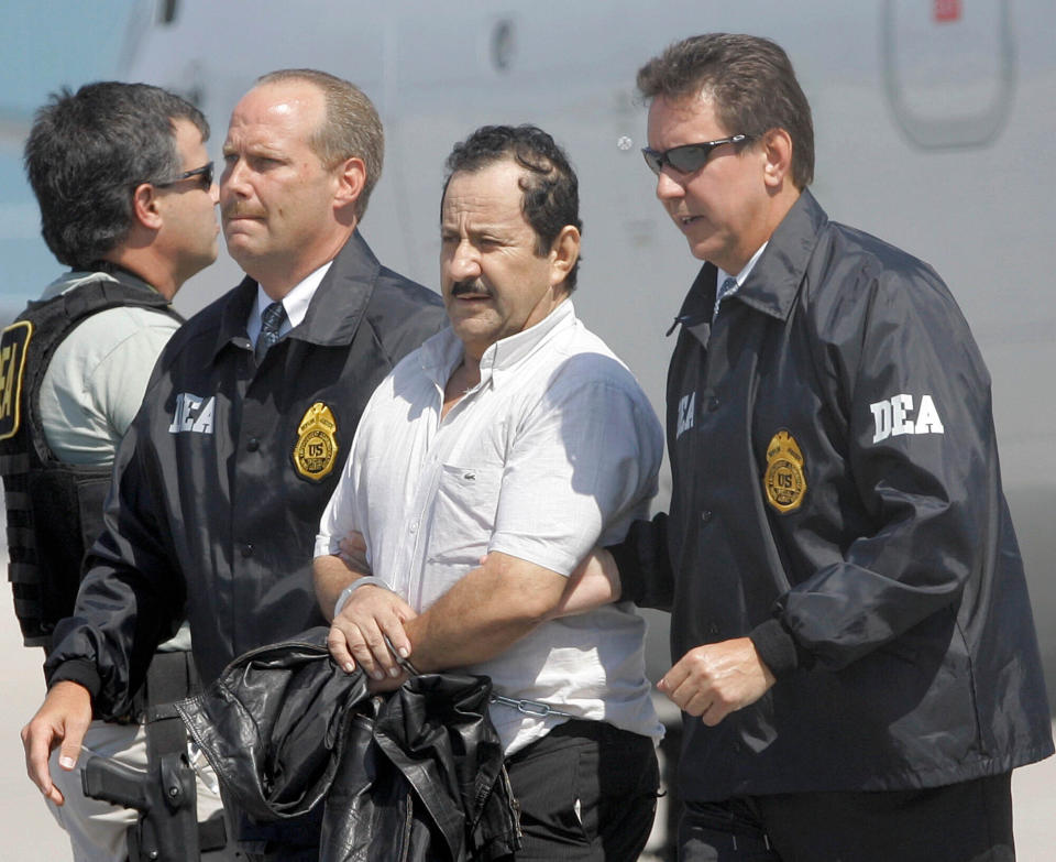 FILE - In this May 13, 2008 file photo, Colombian paramilitary Hernan Giraldo Serna, second right, is escorted by U.S. DEA Agents at his arrival in Opa-locka, Fla. Giraldo Serna has been deported from the US and returned to Colombian on Monday, January 25, 2021, after finishing a 16-year sentence in a U.S. prison for drug trafficking earlier this month. (AP Photo/Alan Diaz, File)