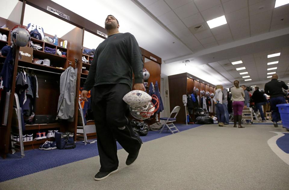 New England Patriots rookie free-agent, defensive tackle Joe Vellano, walks past quarterback Tom Brady's locker carrying an autographed team ball and a helmet at the NFL football team's facility in Foxborough, Mass., Monday, Jan. 20, 2014. The Patriots lost to the Denver Broncos in the AFC Championship game Sunday in Denver ending their season. (AP Photo/Stephan Savoia)