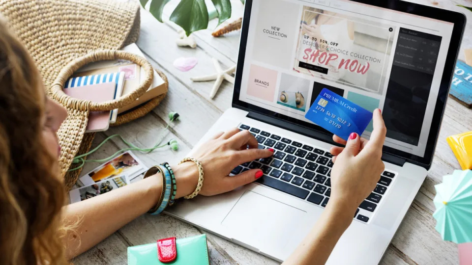 A woman holding a credit card shops online.