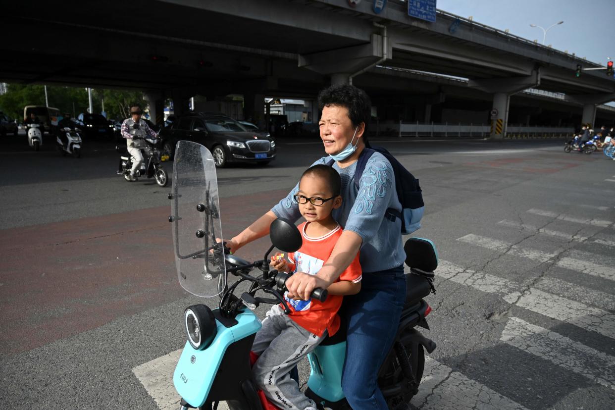 File: A woman carries a child on her electric bike in Beijing on 2 June, 2021 (AFP via Getty Images)