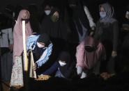 Family members mourn during the burial of their relative at the special section of the Pedurenan cemetery designated to accommodate the surge in deaths during the coronavirus outbreak in Bekasi, West Java, Indonesia, Friday, July 30, 2021. Indonesia surpassed the grim milestone of 100,000 official COVID-19 deaths on Wednesday, Aug. 4, 2021, as the country struggles with its worst pandemic year fueled by the delta variant, with growing concerns that the actual figure could be much higher with people also dying at home. (AP Photo/Achmad Ibrahim)