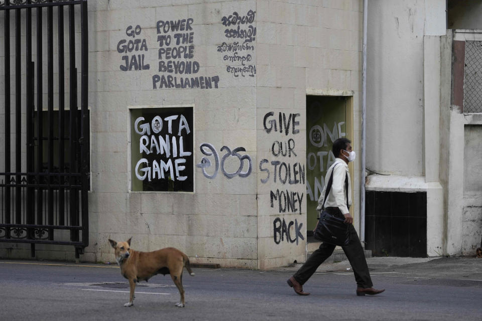 A man walks past a vandalised security point outside president's official residence in Colombo, Sri Lanka, Friday, July 15, 2022. Protesters retreated from government buildings Thursday in Sri Lanka, restoring a tenuous calm to the economically crippled country, and the embattled president at last emailed the resignation that demonstrators have sought for months.(AP Photo/Eranga Jayawardena)