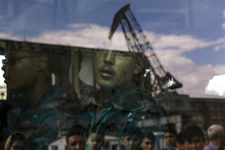 An Afghan migrant is seen inside a bus following his arrival by the Eleftherios Venizelos passenger ferry with over 2,500 migrants and refugees from the island of Lesbos at the port of Piraeus, near Athens, Greece, October 8, 2015. REUTERS/Yannis Behrakis