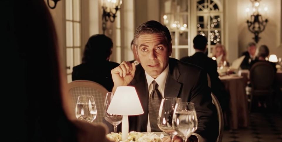 Man speaking over a dinner table in "Intolerable Cruelty"