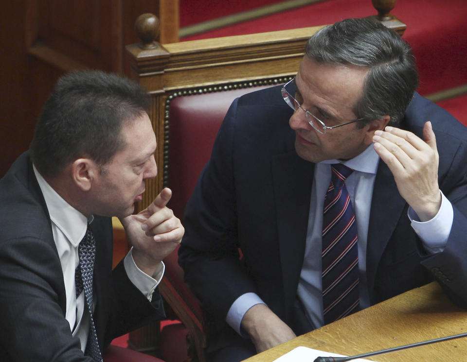 Greece's Prime Minister Antonis Samaras, right, speaks with Greece's Finance Minister Yannis Stournaras during a vote on a privatization bill at the Greek parliament in Athens, Wednesday, Oct. 31, 2012. Greek lawmakers are to vote Wednesday on a privatization bill that will be the first major test for the country's troubled governing coalition, while journalists have walked off the job at the start of rolling 24-hour strikes to protest austerity plans that will affect their healthcare funds. (AP Photo/Thanassis Stavrakis)