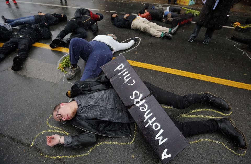 Demonstrators lay on the ground with chalk outlines to represent a mock crime scene during a protest marking the 100th day since the shooting death of Michael Brown in St. Louis