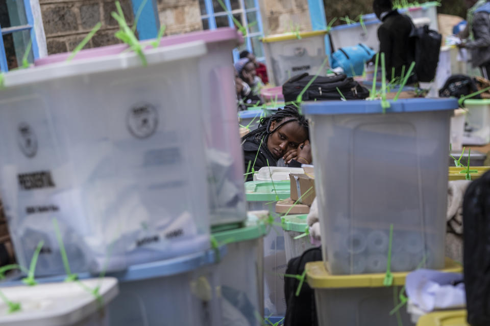 A weary electoral worker rests her head on ballot boxes as she waits in a queue for them to be stored at a collection and tallying center in Nairobi, Kenya Wednesday, Aug. 10, 2022. Kenyans are waiting for the results of a close but calm presidential election in which the turnout was lower than usual. (AP Photo/Ben Curtis)