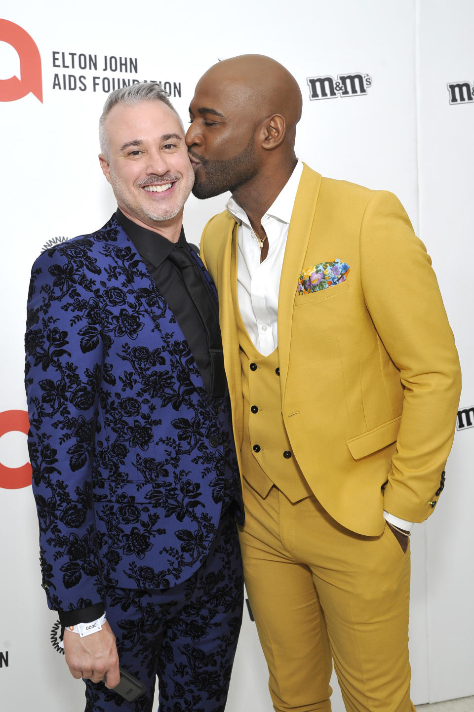 Karamo kissing a smiling Ian on the cheek at a media event