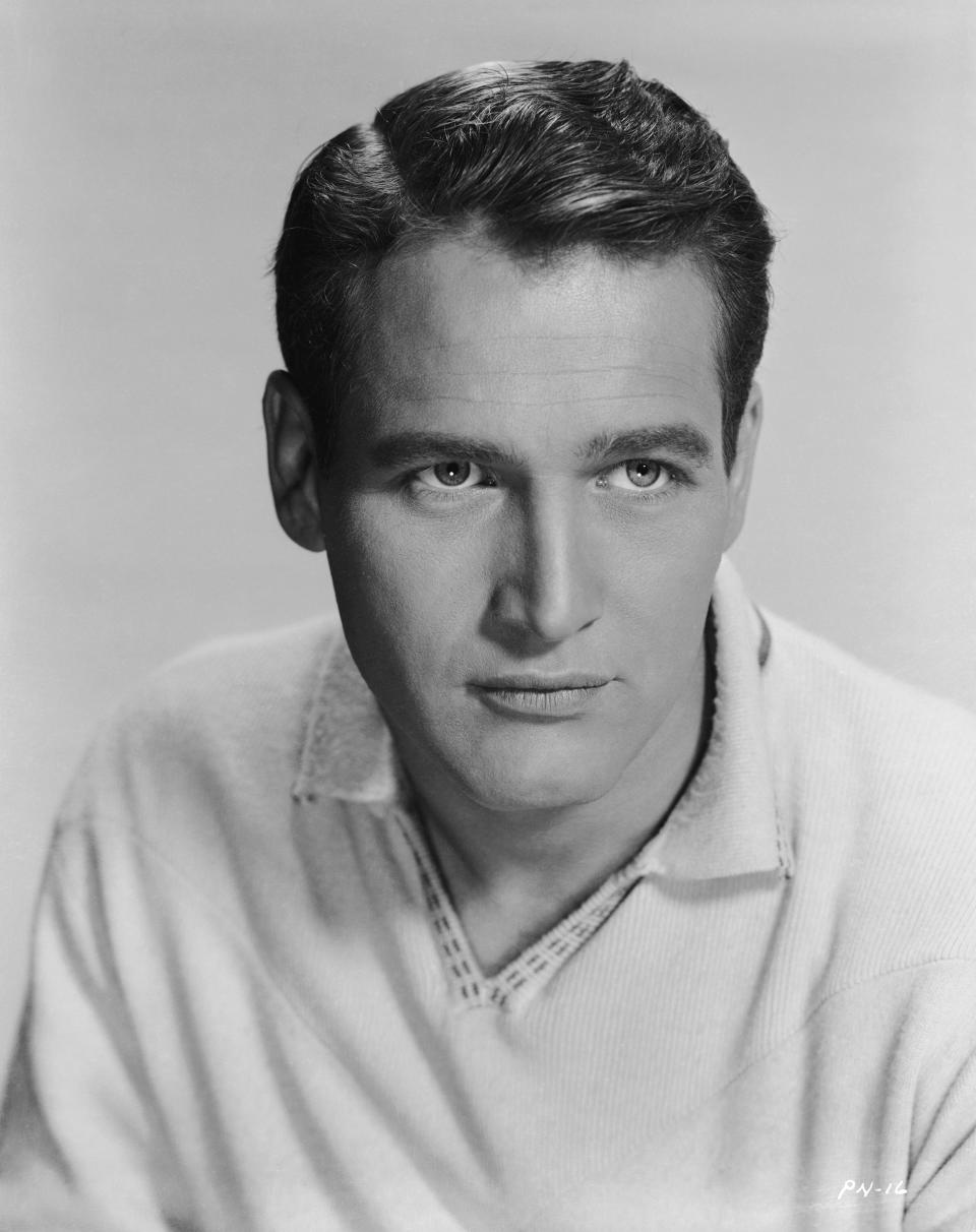 Paul Newman in a mid-20th century-style portrait, wearing a light V-neck sweater and looking engaged