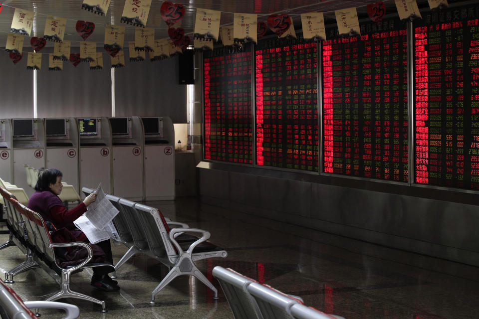 FILE - In this Jan. 18, 2019, file photo, a woman reads a newspaper at a brokerage house in Beijing. Shares rose in Shanghai and Hong Kong on Monday, Jan. 21, 2019, as China reported that its growth fell to a three-decade low of 6.6 percent in 2018. The weaker data released Monday raised hopes for additional moves to shore up support for lagging business activity, though benchmarks fell back slightly from stronger gains just after markets opened. (AP Photo/Andy Wong, File)