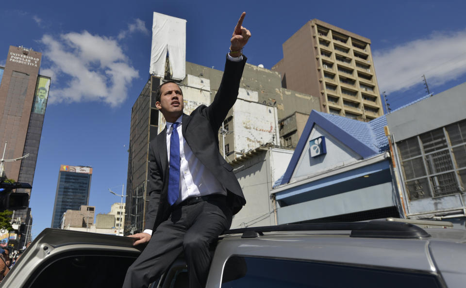 Opposition leader Juan Guaido points to a bus carrying his fellow opposition lawmakers as they are temporarily blocked by national police from reaching a session at the National Assembly, a few blocks from the legislature in Caracas, Venezuela, Tuesday, Jan. 7, 2020. Venezuela’s opposition is facing its biggest test yet after government-backed lawmakers announced they were taking control of what Guaidó supporters have described as the nation’s last democratic institution. (AP Photo/Matias Delacroix)