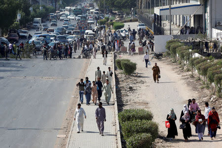 People walk after crossing the blockades put up by the supporters of the Tehreek-e-Labaik Pakistan, an Islamist political party, along the main road leading to the airport in Karachi, Pakistan November 25, 2017. REUTERS/Akhtar Soomro