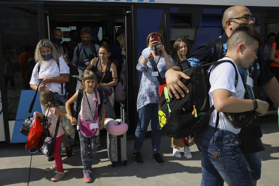 Ukrainian refugees leave a bus before boarding a plane transporting them to Canada, from Frederic Chopin Airport in Warsaw, Poland, Monday, July 4, 2022. Phan Thị Kim Phuc, the girl in the famous 1972 Vietnam napalm attack photo, on Monday escorted 236 refugees from the war in Ukraine on a flight from Warsaw to Canada. Phuc’s iconic Associated Press photo in which she runs with her napalm-scalded body exposed, was etched on the private NGO plane that is flying the refugees to the city of Regina. (AP Photo/Michal Dyjuk)