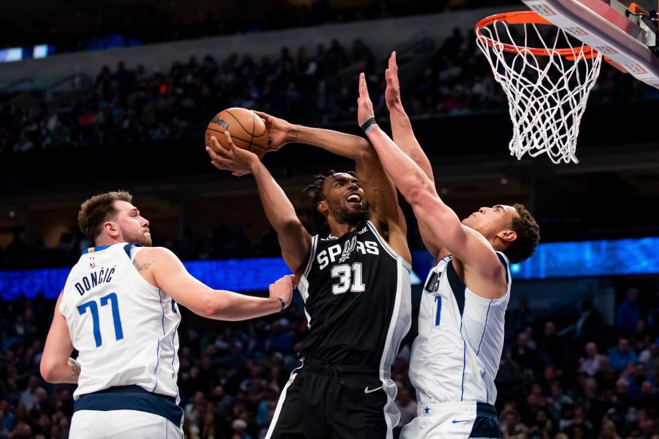 San Antonio Spurs forward Keita Bates-Diop (31) attempts to score over Dallas Mavericks center Dwight Powell (7) after driving past Mavericks guard Luka Doncic (77) in the first half of an NBA basketball game Thursday, Feb. 23, 2023, in Dallas. (AP Photo/Emil T. Lippe)