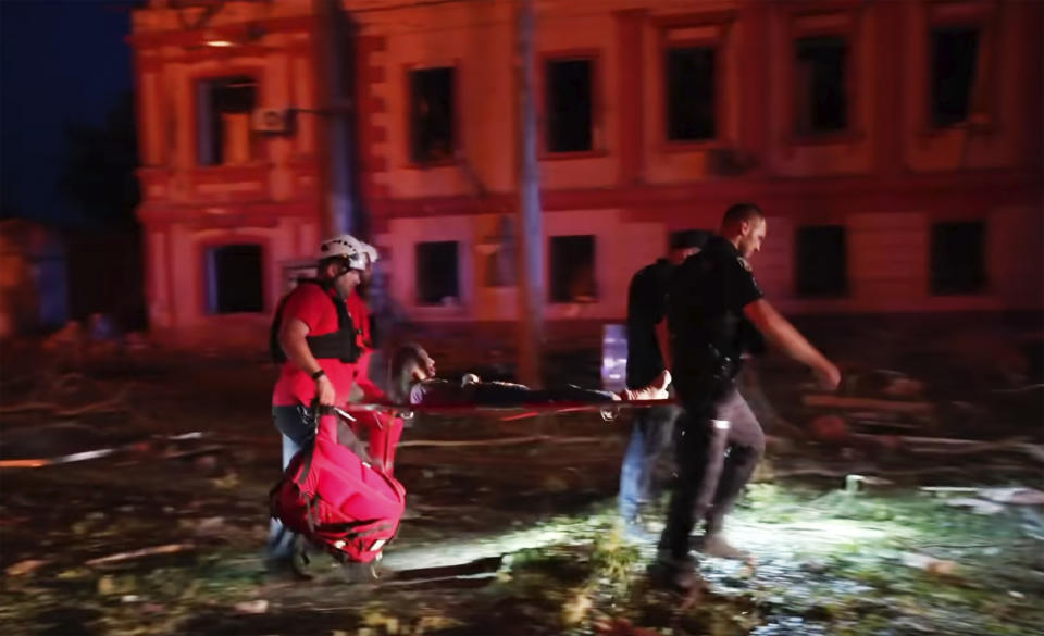 In this image taken from video provided by the Ukrainian Emergency Service, emergency workers carry an injured woman after a Russian attack on residential area in Mykolaiv, Ukraine, Thursday, July 20, 2023. (Ukrainian Emergency Service via AP)