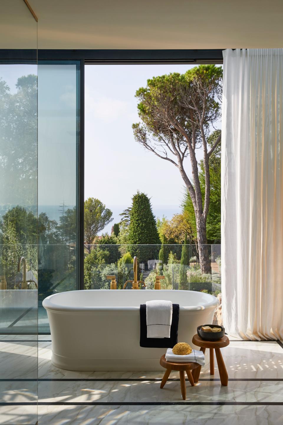 Bathtub by Devon & Devon, Volevatch polished brass taps, Charlotte Perriand stools, and Nobilis curtains.