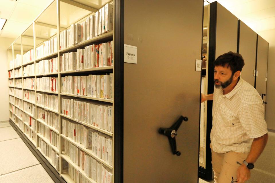 Forensic scientist Chris Wise shows on the pistols logged into evidence for analysis at the Mississippi State Crime Lab in Pearl in June.