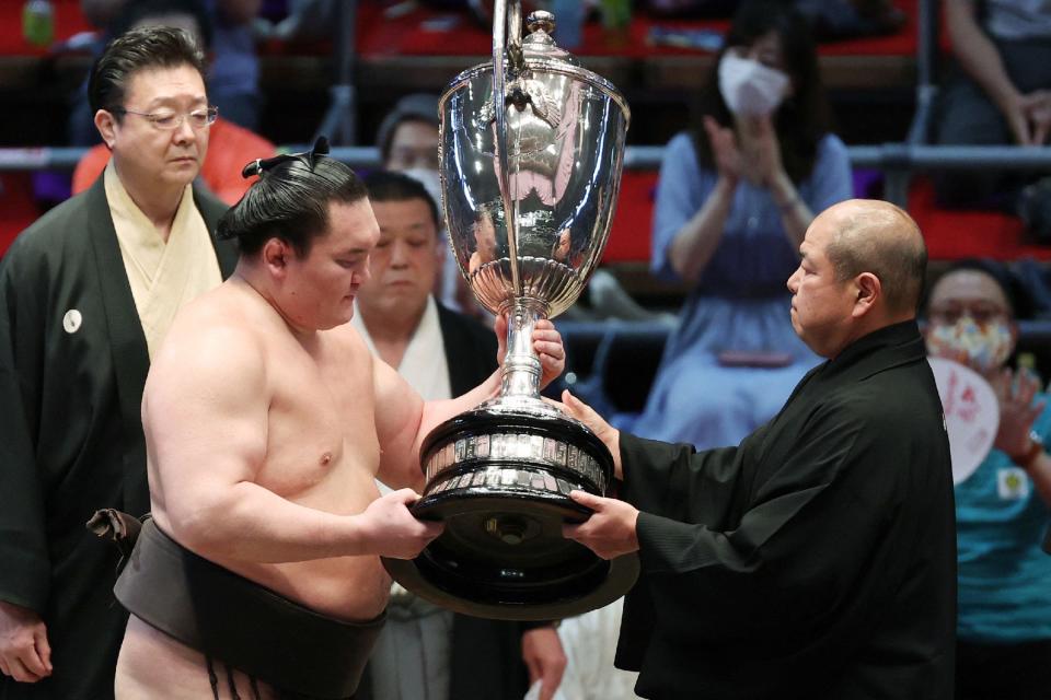 Yokozuna-ranked, or grand champion, sumo wrestler Hakuho (front L) receives the championship trophy at the awards ceremony after beating ozeki-ranked wrestler Terunofuji, both originally from Mongolia, to finish with a perfect 15-0 record for his 45th career tournament championship.