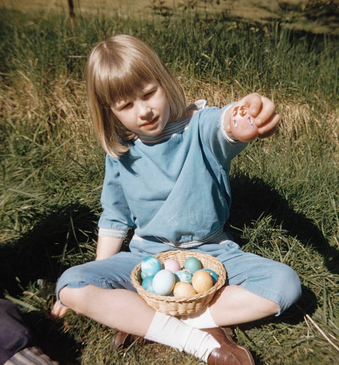 a vintage photo of a young child holding a basket of easter eggs in their lap