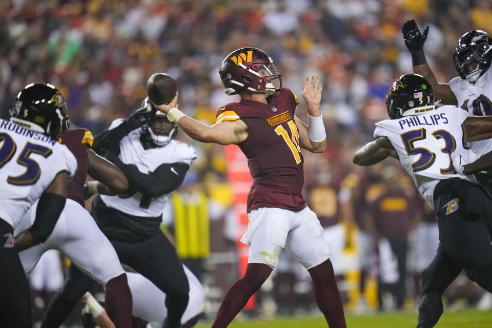 Washington Commanders quarterback Sam Howell, center, looks to throw a pass under pressure during the first half of an NFL preseason football game against the Baltimore Ravens, Monday, Aug. 21, 2023, in Landover, Md. (AP Photo/Julio Cortez)