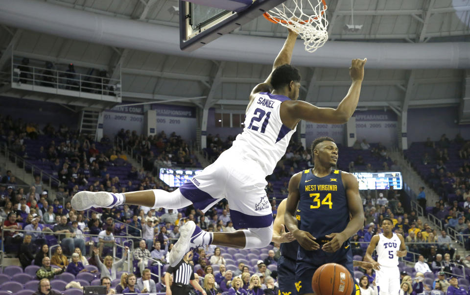 TCU center Kevin Samuel (21) hangs on the rim following his dunk as West Virginia forward Oscar Tshiebwe (34) looks on during the second half of an NCAA college basketball game, Saturday, Feb. 22, 2020 in Fort Worth, Texas. TCU won in overtime. (AP Photo/Ron Jenkins)