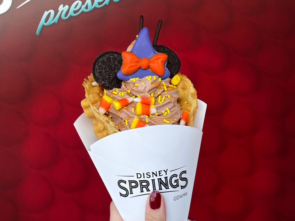hand holidng a minnie witch waffle cone at disney springs