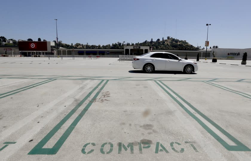LOS ANGELES, CALIF. - MAY 27, 2020. A car rolls through the empty parking lot of Eagle Rock Plaza shopping center in Eagle Rock on Wednesday, May 27, 2020. Stores remained mostly closed despite restrictions being lifted for for in-store shopping throughout California. (Luis Sinco/Los Angeles Times)