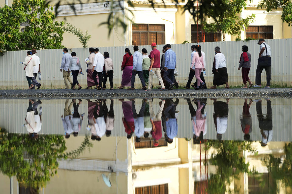 People are reflected in water as they arrive for the hearings against Khieu Samphan, former Khmer Rouge head of state, at the U.N.-backed war crimes tribunal in Phnom Penh, Cambodia, Thursday, Sept. 22, 2022. An international court in Cambodia will issue its ruling on an appeal by Khieu Samphan, the last surviving leader of the Khmer Rouge government that ruled the Southeast Asian country from 1975-79. He was convicted in 2018 of genocide, crimes against humanity and war crimes and sentenced to life in prison. (AP Photo/Heng Sinith)