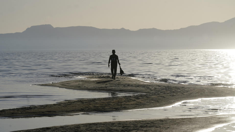 FILE - A man walks along a sand bar at the receding edge of the Great Salt Lake on June 13, 2021, near Salt Lake City. The water levels at the Great Salt Lake have hit a historic low, a grim milestone for the largest natural lake west of the Mississippi River that comes as a megadrought grips the region. (AP Photo/Rick Bowmer, File)