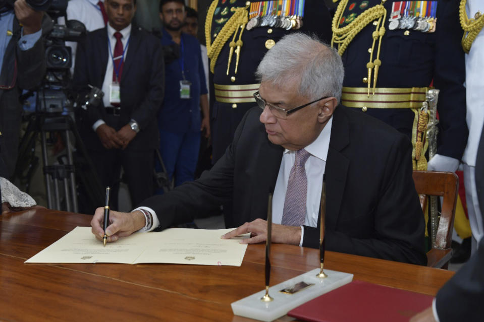 In this photo provided by Sri Lankan President's Office, Sri Lanka's newly elected president Ranil Wickremesinghe, signs after taking oath during his swearing in ceremony in Colombo, Sri Lanka, Thursday, July 21, 2022. (Sri Lankan President's Office via AP)