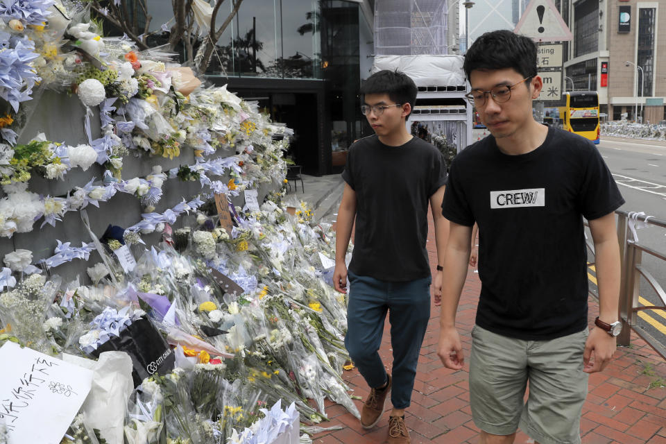 Pro-democracy activist Joshua Wong, left, is accompanied by Nathan Law as they arrive at a makeshift memorial to a pay respect to a protester who fell to his death after hanging a protest banner against an extradition bill in Hong Kong, Monday, June 17, 2019. Wong, a leading figure in Hong Kong's 2014 Umbrella Movement demonstrations, was released from prison on Monday and vowed to soon join the latest round of protests. (AP Photo/Kin Cheung)